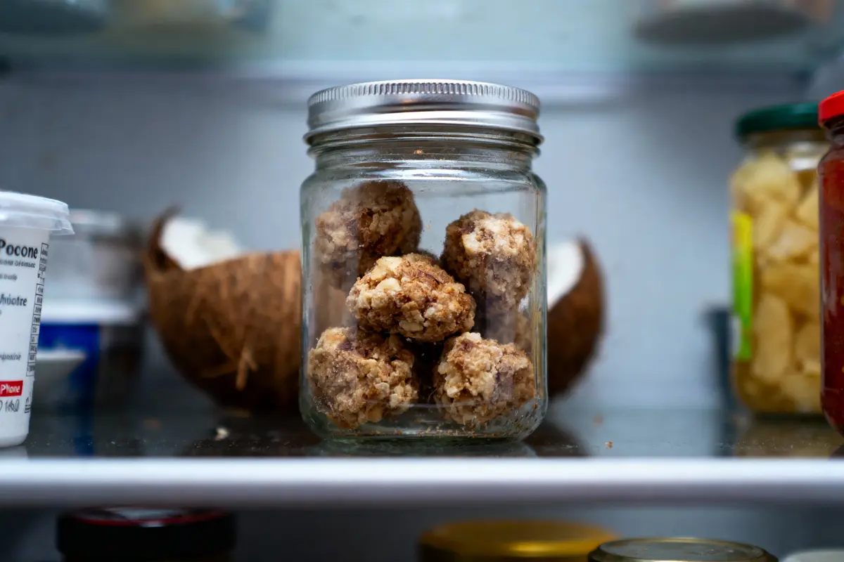pexels-michal-pech-213601-757318 (1) Pot en verre avec boules d'énergie, noix de coco en arrière-plan, vue dans un réfrigérateur plein.