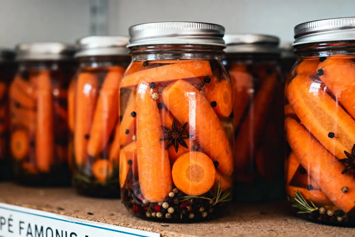 Bocaux de carottes marinées avec épices, étagère en cuisine.