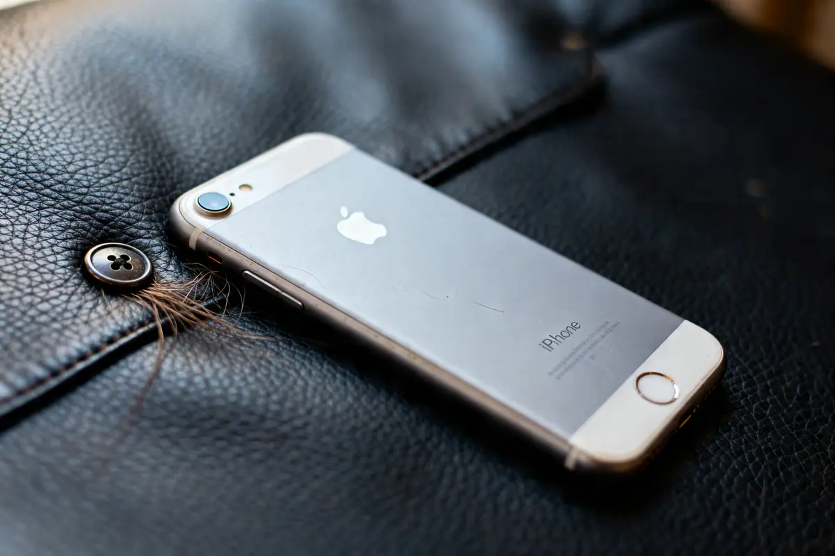 iPhone sur cuir avec bouton, mèche de cheveux évoquant bouton sur le cuir chevelu