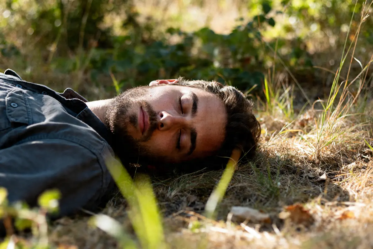 Homme barbu allongé sur l'herbe en plein air pour dormir la tete au nord