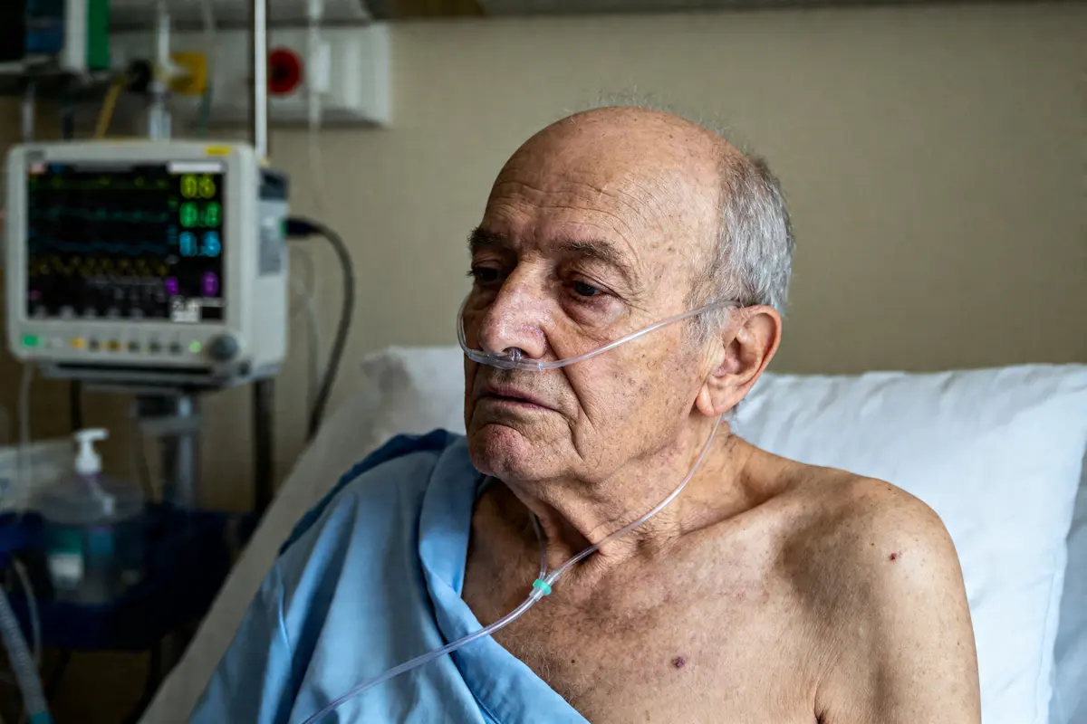 Homme âgé hospitalisé sous oxygène souffrant d'emphysème pulmonaire et monitoring médical visible
