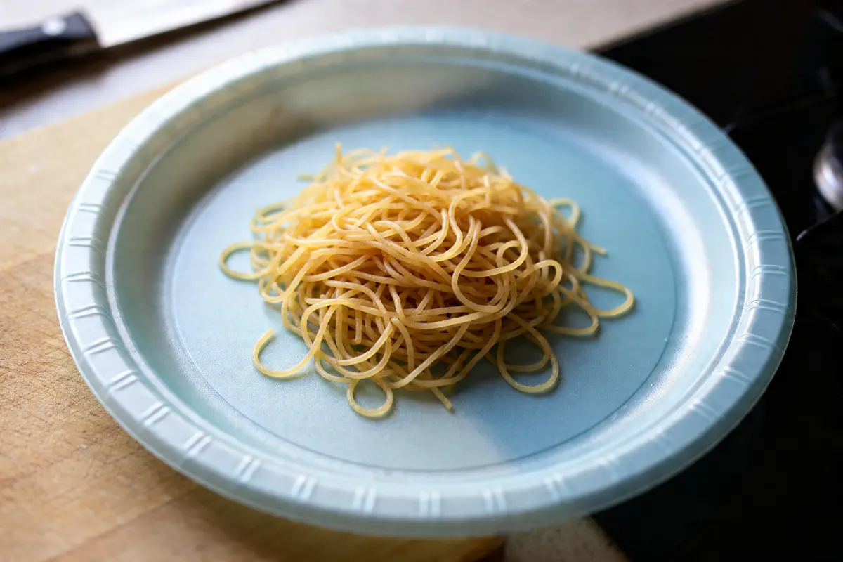 Assiette avec quantité de vermicelle par personne posée sur une table en bois