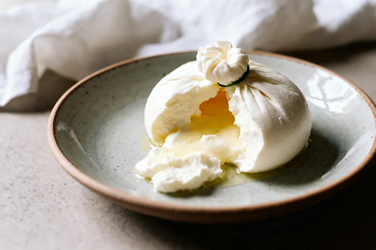 Burrata crémeuse éclatée sur assiette, découvrant sa texture moelleuse et burrata nutrition facts.