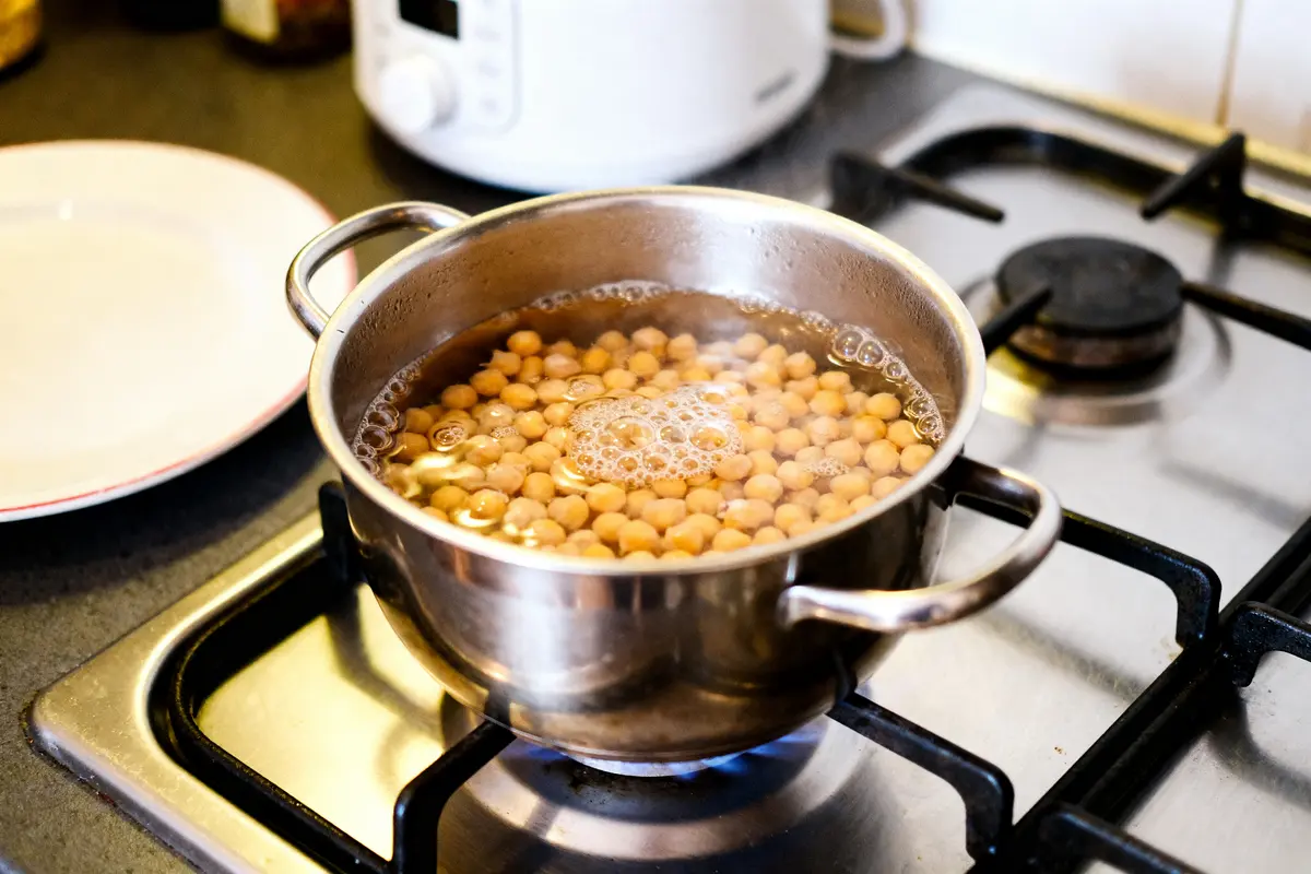 Casserole cuisant des pois chiches bouillonnants sur un feu pour le temps de cuisson optimal